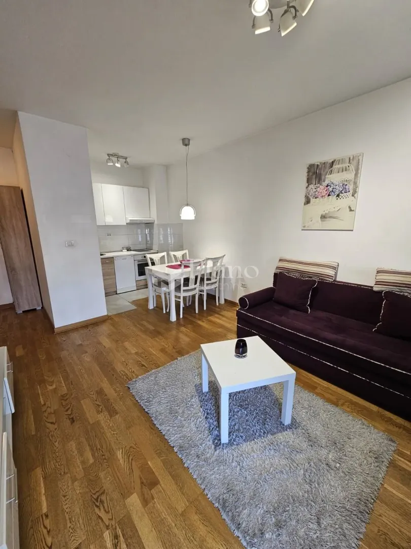 Living room with a sofa, dining area, and kitchen in the background.