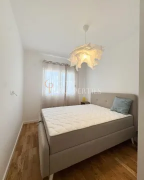 Manja spavaća soba sa bračnim krevetom, bijelim zidovima i drvenim podom. - image 6