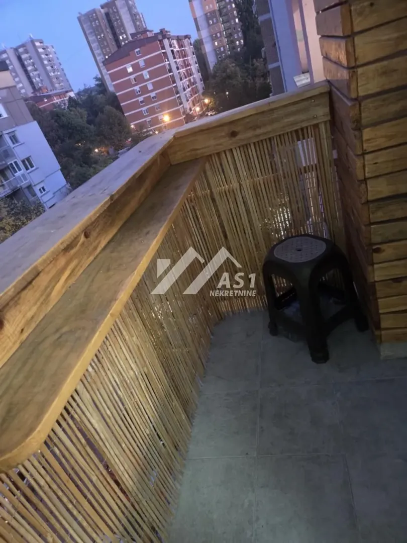 Manji balkon opremljen drvenim detaljima i stolicom.