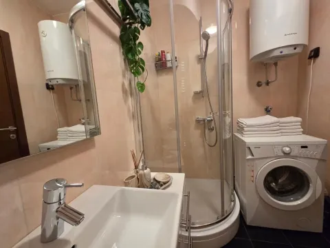 Smaller bathroom with a shower cabin, sink, and washing machine. - image 16