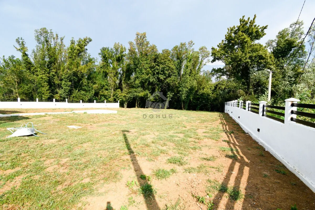 Fenced yard with lawn and forest view.