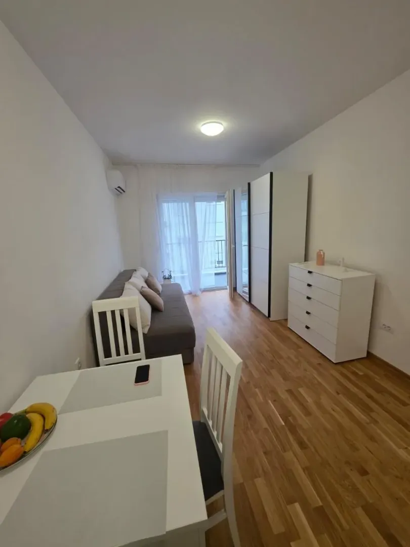 Dnevni boravak sa garniturom, trpezarijskim stolom i ormarima.