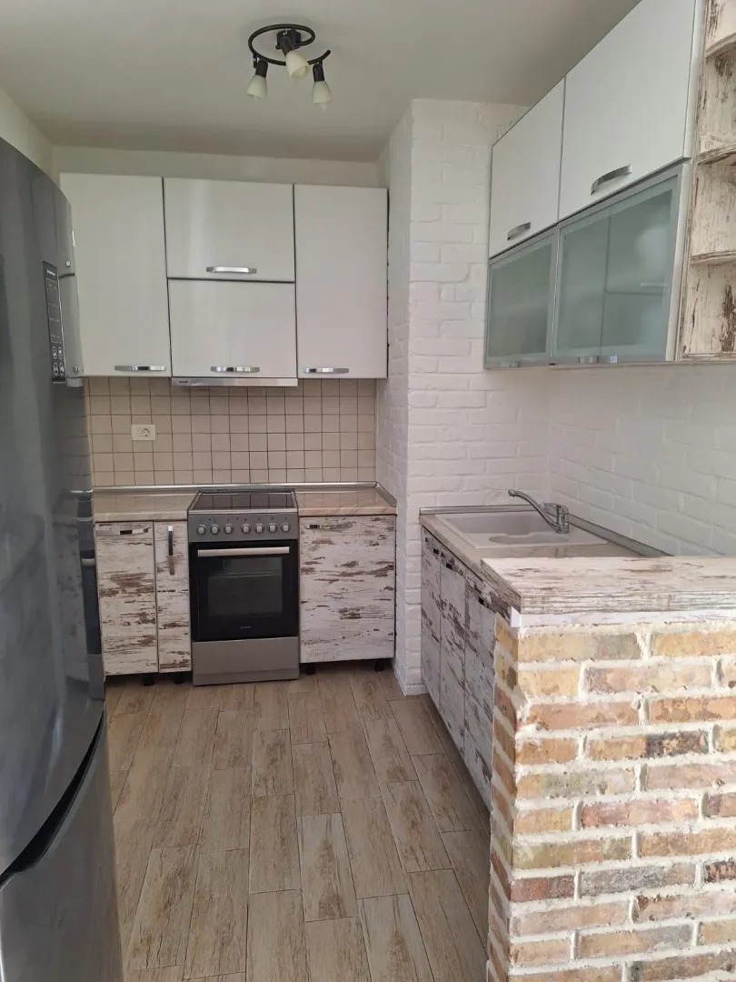 Smaller equipped kitchen with white cabinets and a brick breakfast bar.