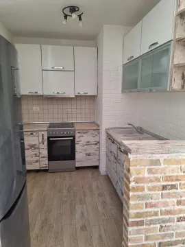 Smaller equipped kitchen with white cabinets and a brick breakfast bar. - image 5