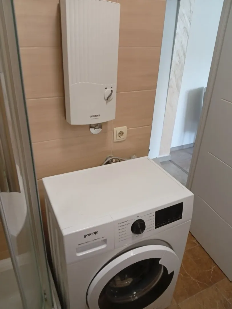 Mašina za pranje veša i protočni bojler u kupatilu.