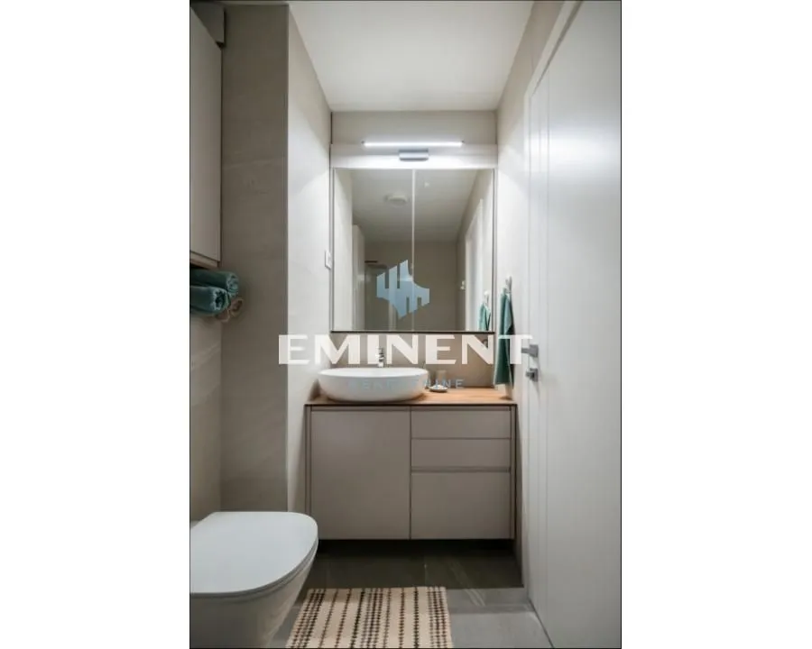 Modern bathroom with a sink, mirror, and toilet.