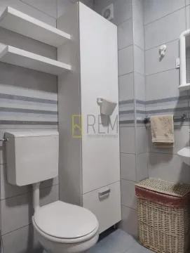 Manje kupatilo sa bijelim ormarićem, wc šoljom i pločicama. - image 6