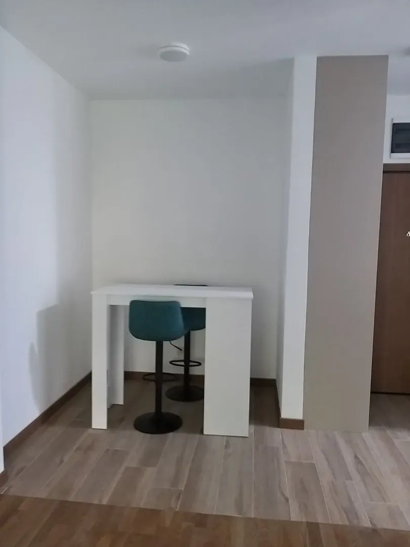 Manja kuhinja sa trpezarijskim stolom i stolicama.
