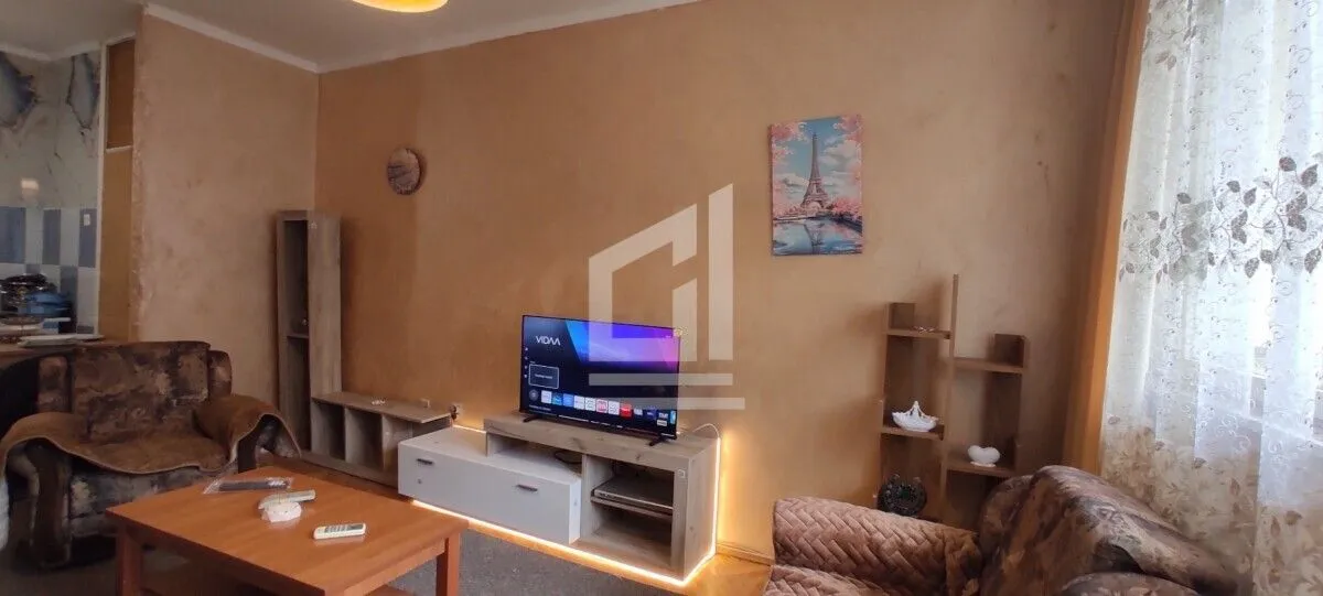 Dnevna soba sa garniturom, televizorom i drvenim namještajem.