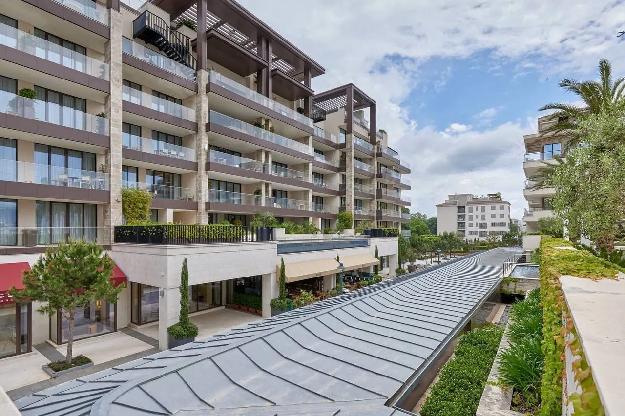 Pogled na moderno stambeno-poslovni kompleks sa uređenim dvorištem i terasama.