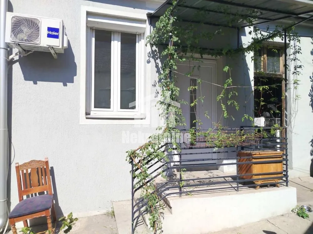 Ulaz u kuću sa stepeništem i nadstrešnicom prekrivenom zelenilom.