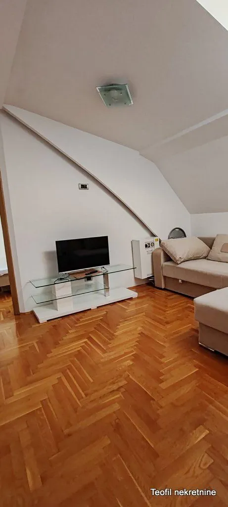 Living room with a sofa, TV stand and parquet flooring.