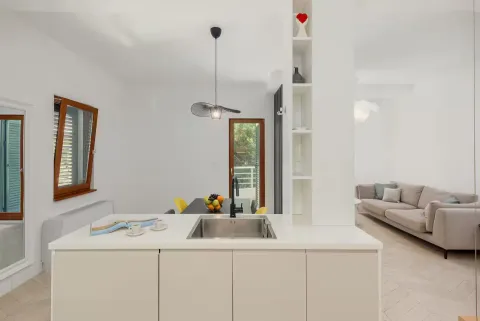 Modern kitchen with a sink on the island and a view of the living room. - image 7