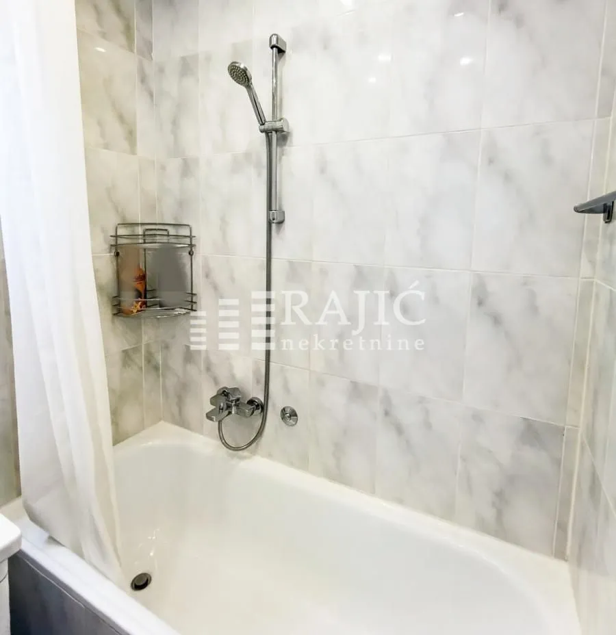 Bathroom with a bathtub and shower fixture.