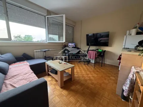 Living room with a sofa, TV and kitchen units in the corner. - image 7
