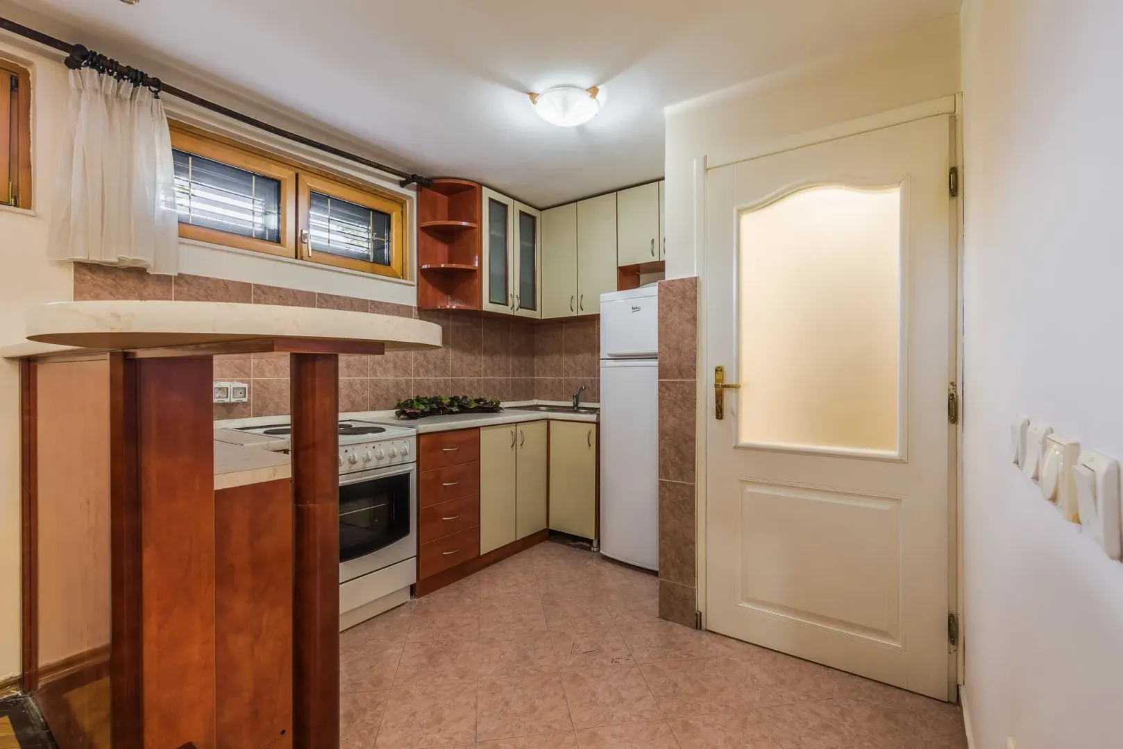 A simple kitchen with wooden elements and appliances.
