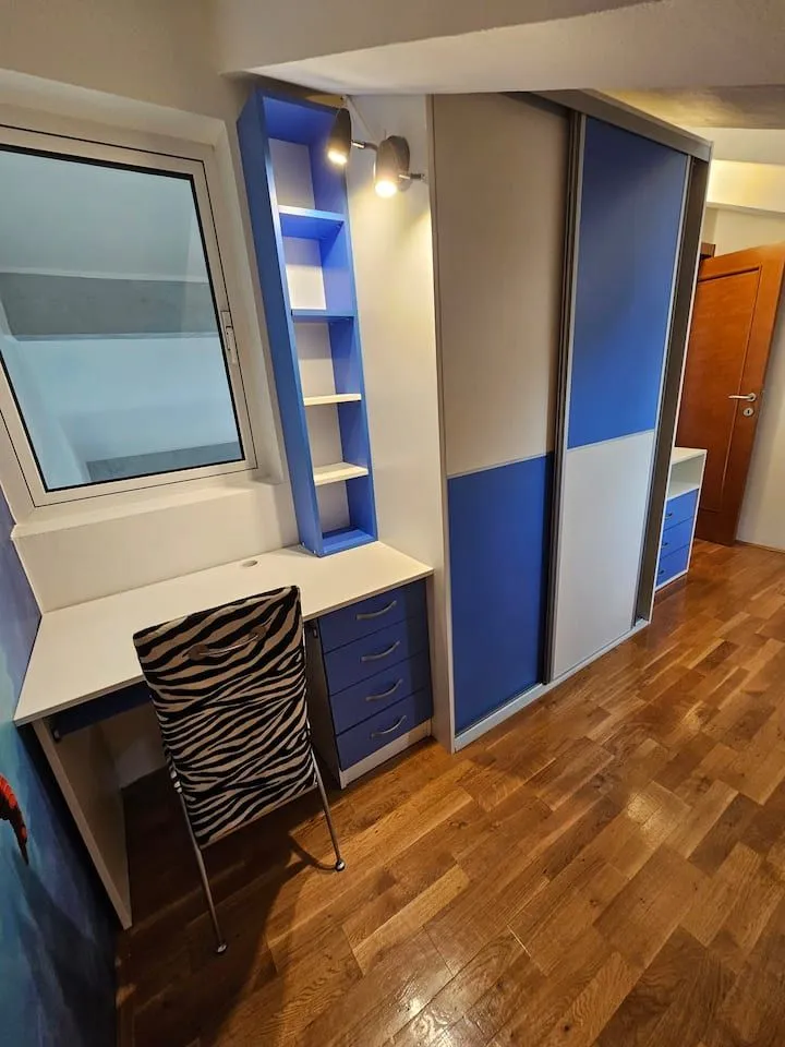 Children's bedroom with a desk, wardrobe, and wooden flooring.