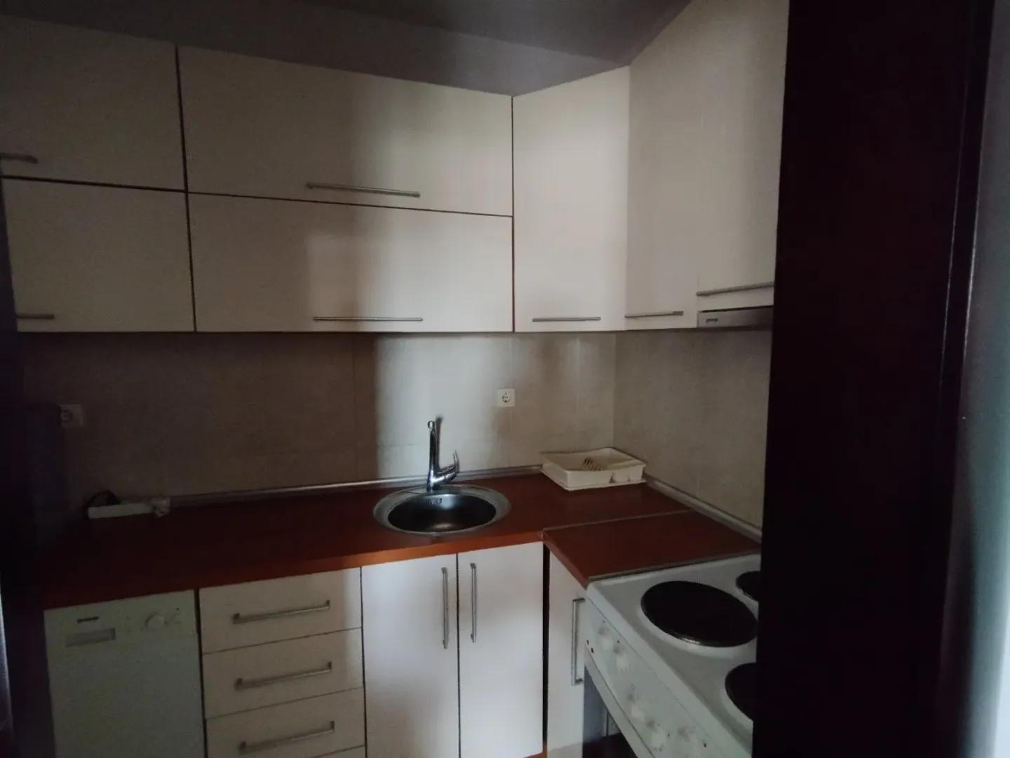 Mala, funkcionalna kuhinja sa bijelim elementima i ugradnom tehnikom.