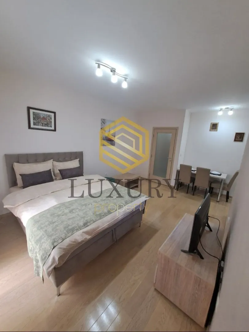 Spacious bedroom with a double bed and a dining area in the background.