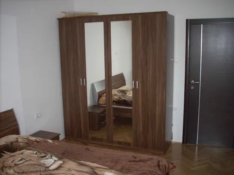 Spavaća soba sa velikim drvenim ormarom koji ima ogledala. - image 3