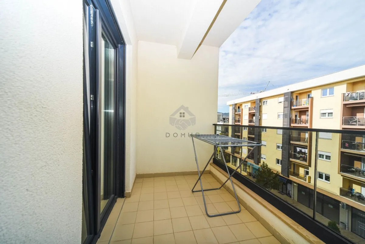 Nenamješten balkon sa staklenom ogradom i stalkom za sušenje veša.
