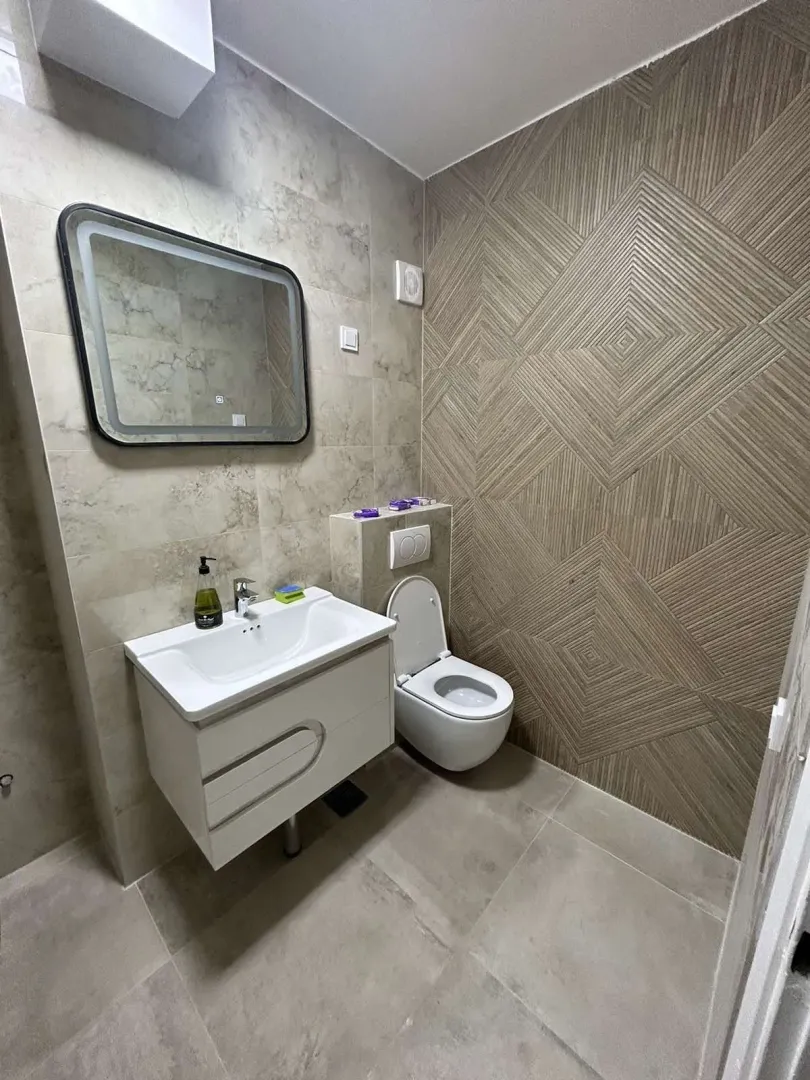 Modern bathroom with a wall-mounted sink and a backlit mirror.