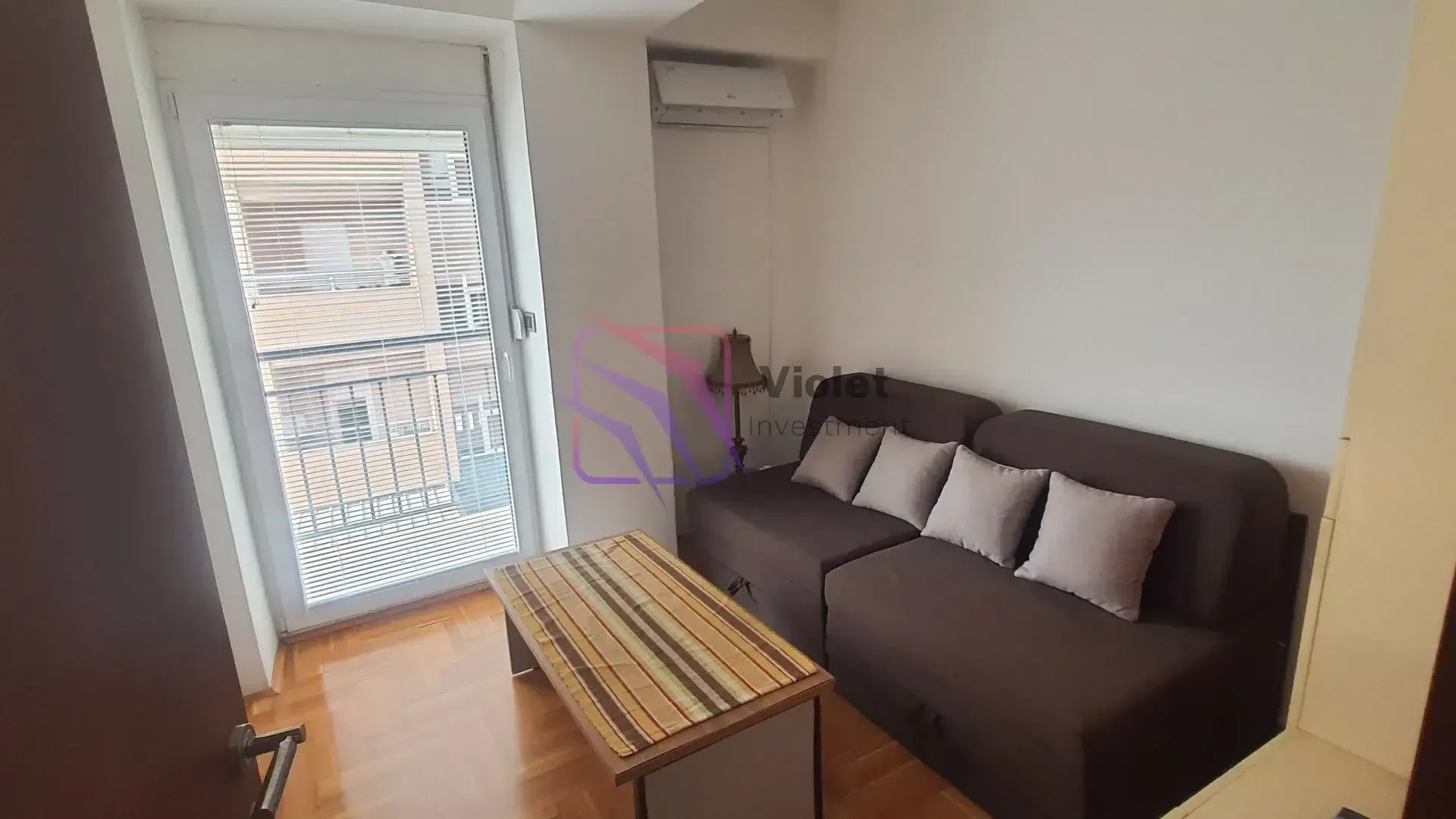 Small living room with a brown sofa, coffee table, and access to the terrace.