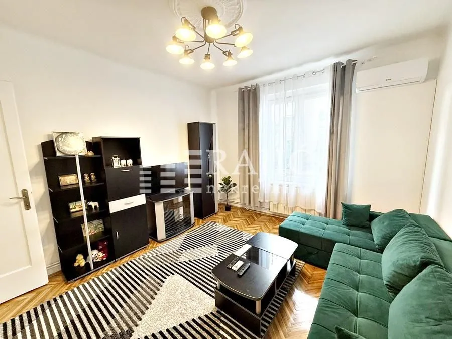 Living room with a green corner sofa, shelving units, and a rug.