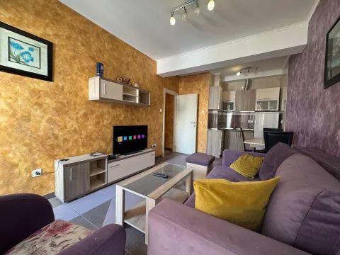 Living room with sofa, TV and a view of the kitchen in the background. - image 3