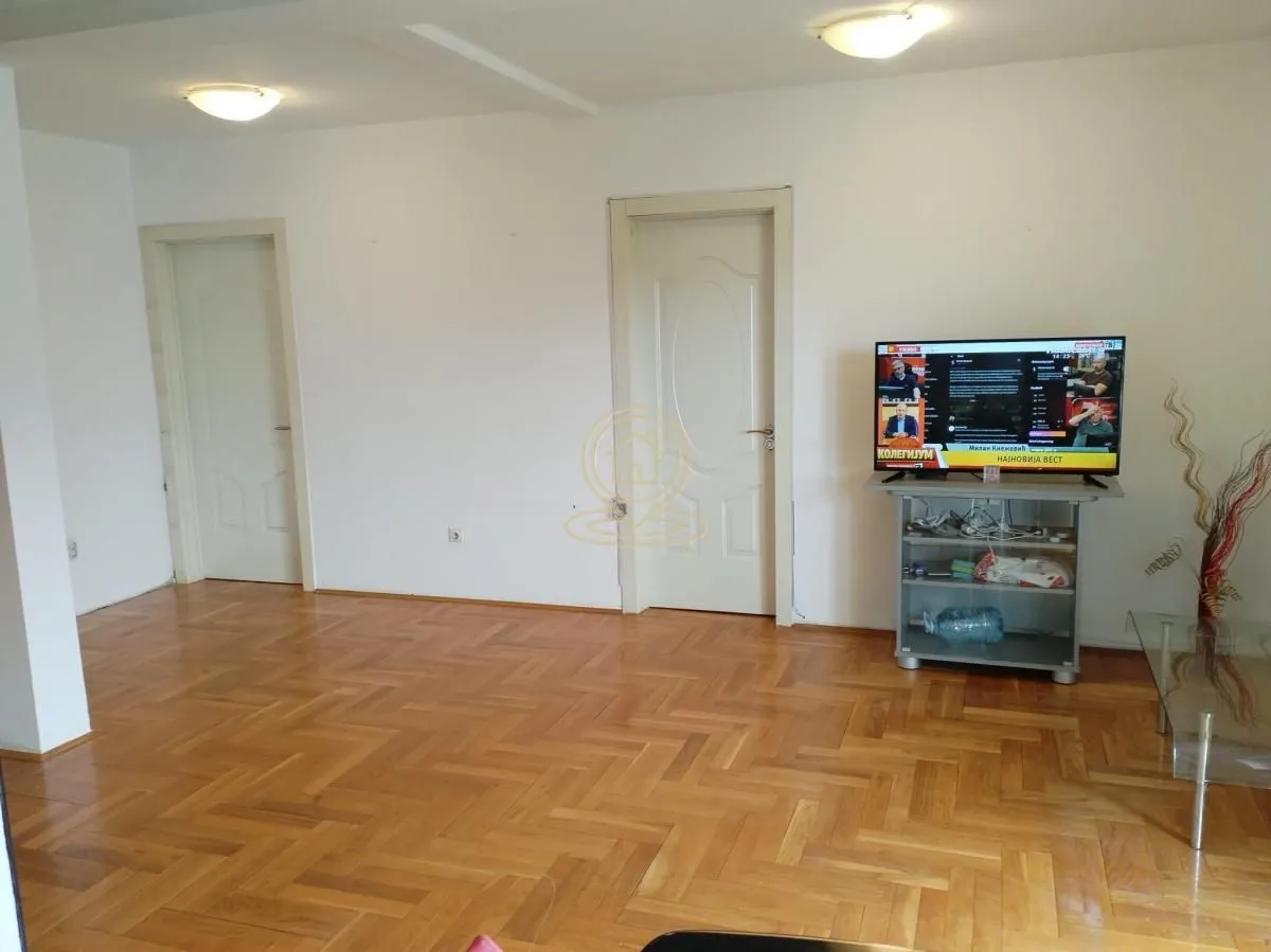 Dnevna soba sa parketom na podu i televizorom.