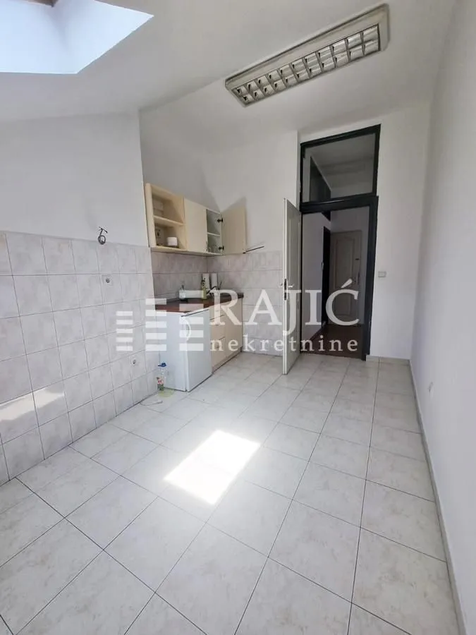 Smaller kitchen with white units and ceramic floor tiles.