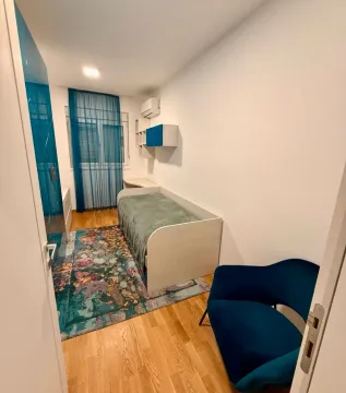 Dječija soba sa krevetom, plavom foteljom i šarenim tepihom. - image 9