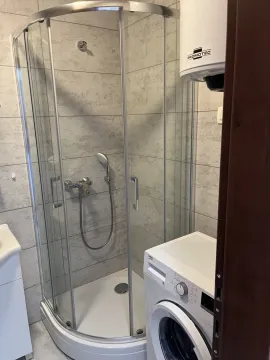 A bathroom featuring a glass shower cabin and a washing machine. - image 12