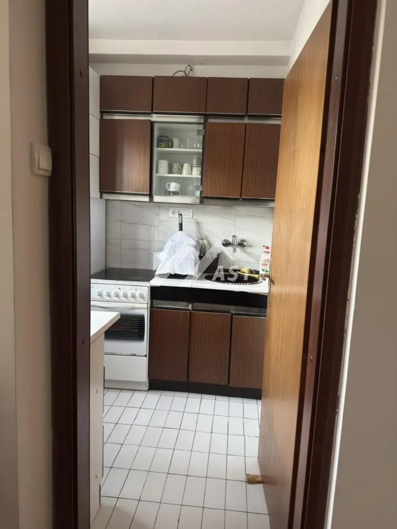 Manja kuhinja sa drvenim elementima i šporetom.
