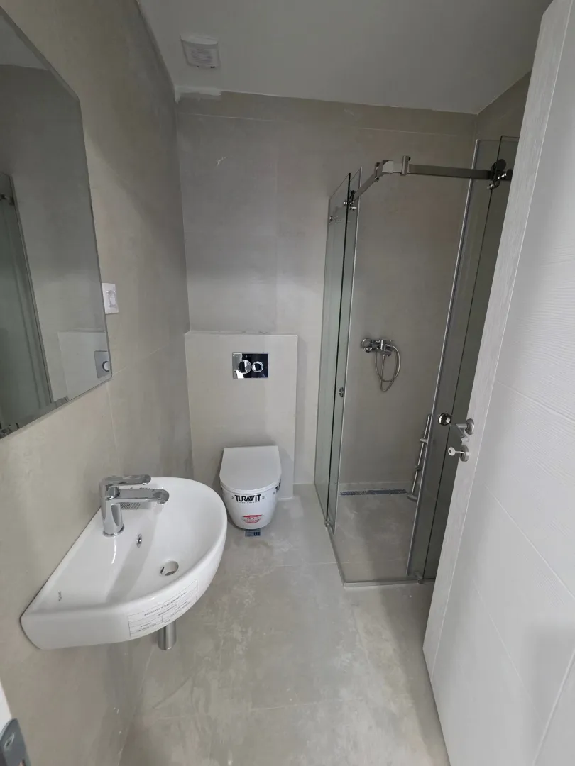 Modern bathroom equipped with a washbasin, toilet, and a glass-enclosed shower.