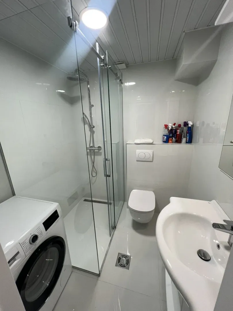 Bright bathroom with a shower cabin and a washing machine.