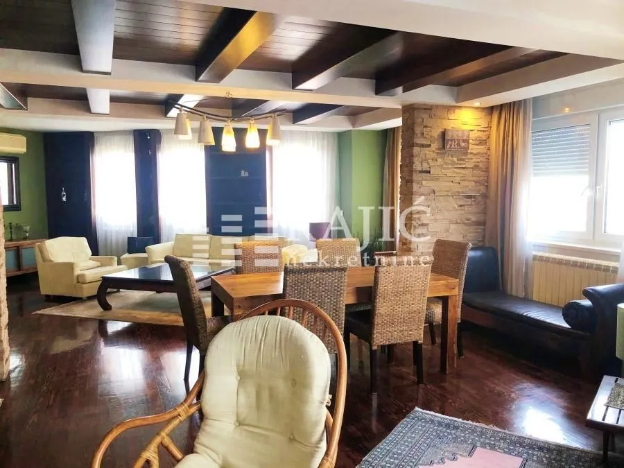 Spacious living room with dining area, wooden ceiling beams, and furniture.