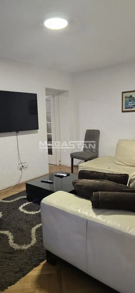 Living room with sofa, coffee table, and wall-mounted TV.