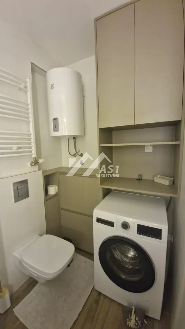 Kupatilo sa wc šoljom, mašinom za veš, bojlerom i ugradnim elementima.