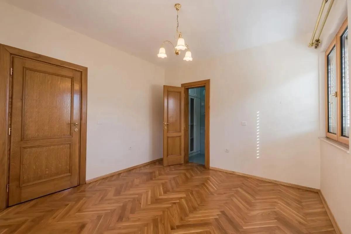 Empty room with parquet flooring and wooden doors.