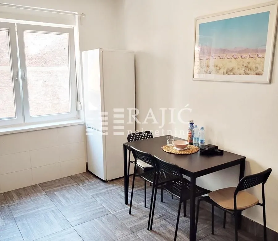 Smaller dining area with a black table and chairs next to the refrigerator.