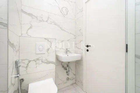Small bathroom with white marble-effect tiles, a washbasin, and a wall-mounted toilet. - image 3