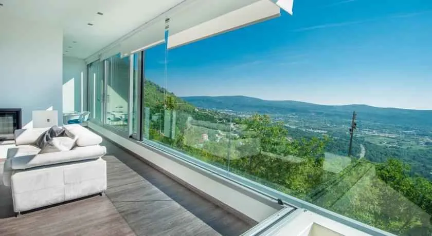 Svijetla dnevna soba sa panoramskim pogledom kroz veliki stakleni zid.