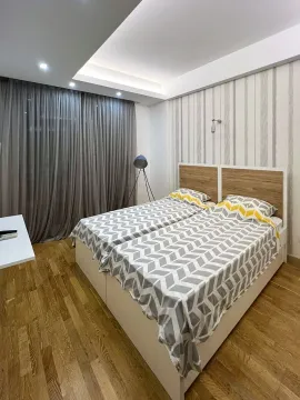 Spavaća soba sa dva spojena kreveta i drvenim podom. - image 7
