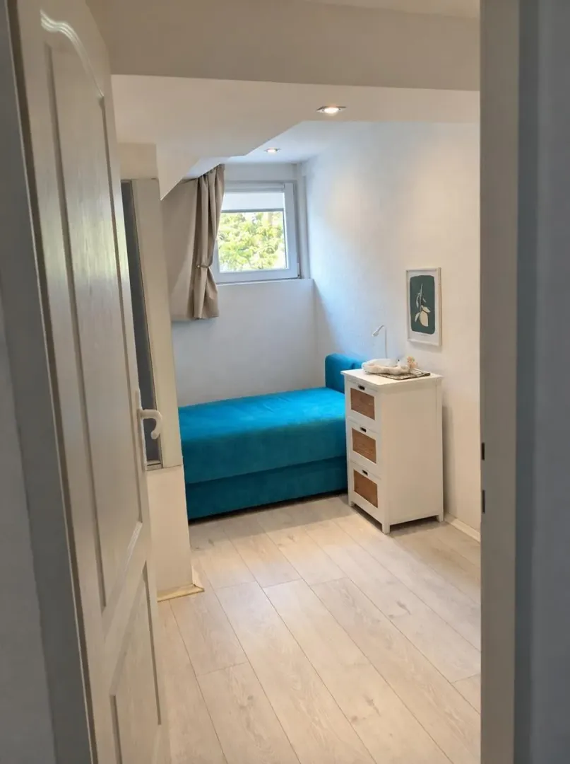 View of a smaller bedroom with a bed and chest of drawers through an open door.