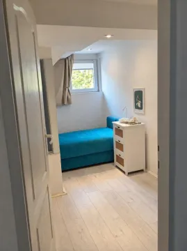View of a smaller bedroom with a bed and chest of drawers through an open door. - image 6