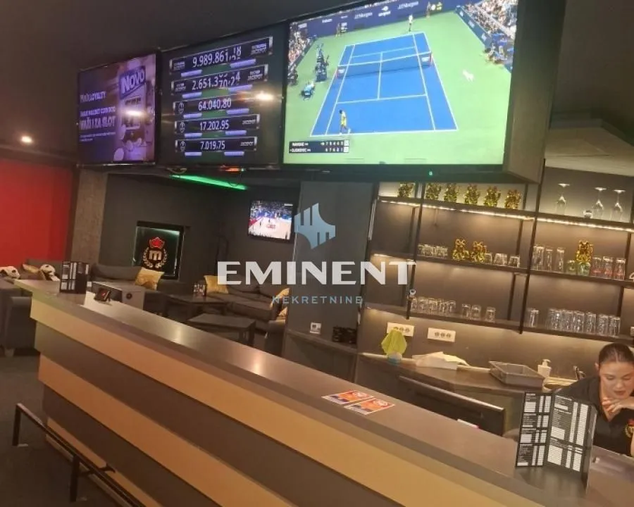 Interior of a commercial space equipped as a bar with screens and seating areas.