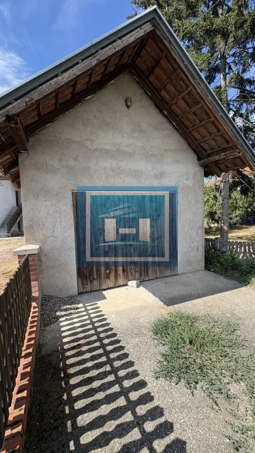 Pogled na spoljašnjost pomoćnog objekta sa drvenim vratima.