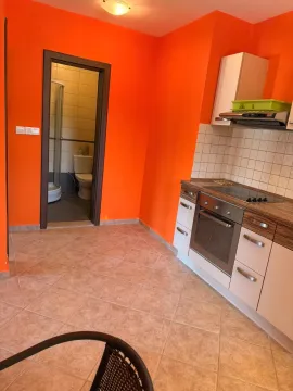 Manja kuhinja sa belim elementima i narandžastim zidovima. - image 8