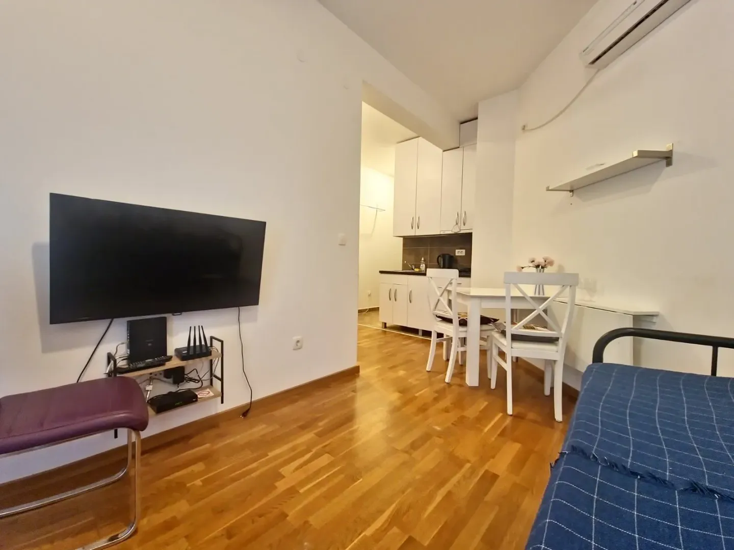 Living room with a TV and a dining area with the kitchen in the background.